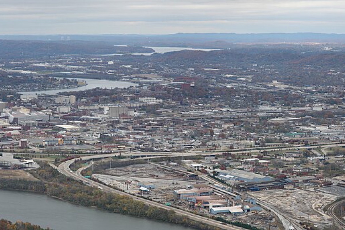 Chattanooga seen from the mountain above it in late autumn, the Tennessee River curving through the middle of the city, rail yards and industry along the near bank and wooded ridges running to the horizon.