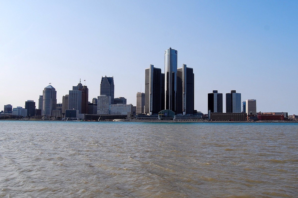 The Detroit riverfront seen from the water, the circular towers of the riverfront centre in the middle and the rest of the skyline running away on both sides under a clear sky.