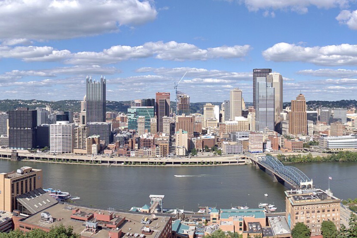 The Pittsburgh point seen from the hill above it, the two rivers meeting at the tip, bridges crossing both, and the whole triangle of office towers packed in behind.