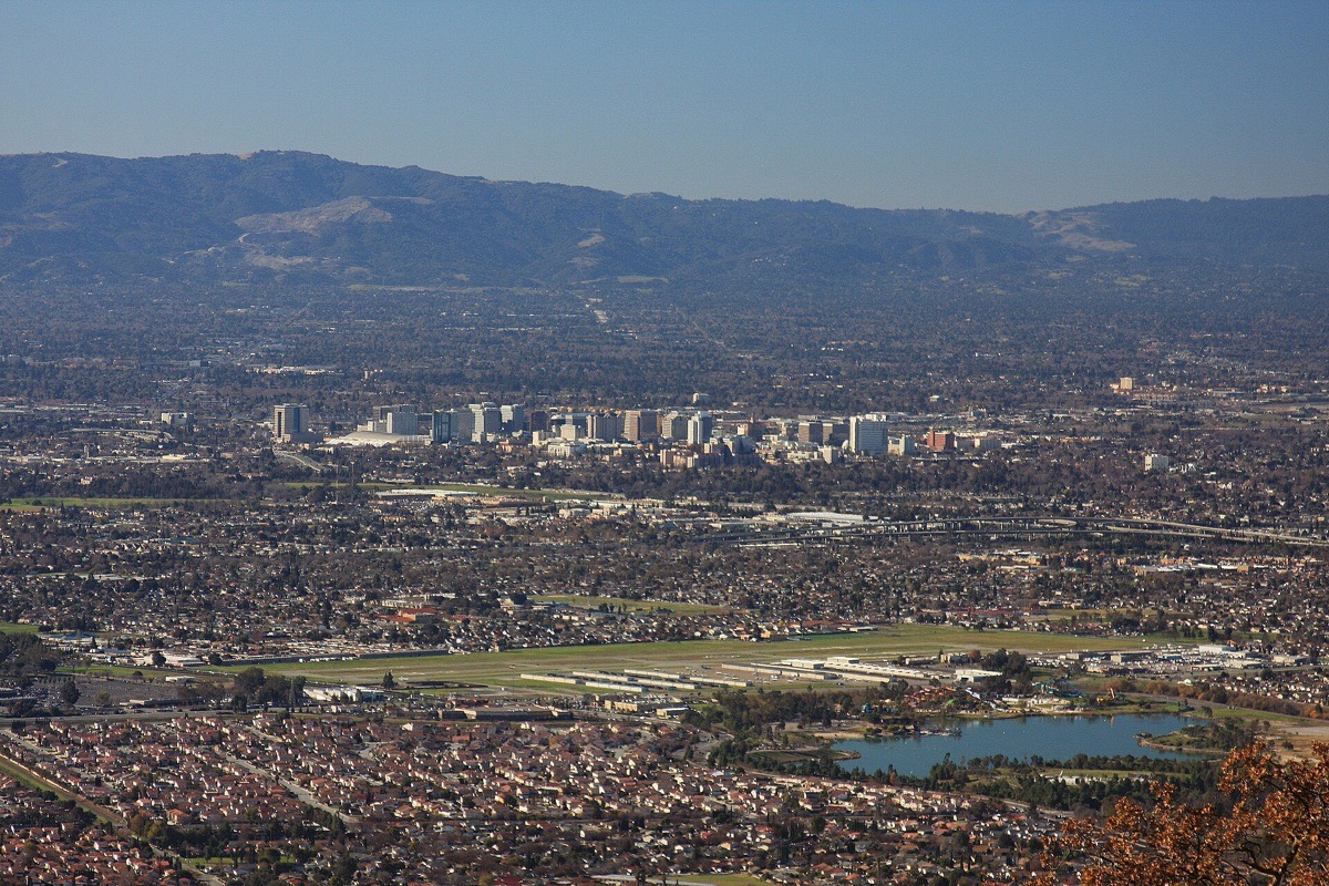 San Jose seen from the hills above it, the office towers of the centre standing small in the middle of a flat valley of houses that runs out to a long range of hills on the far side.