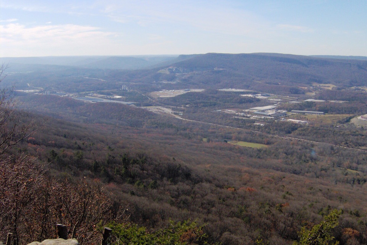 A wide Tennessee valley seen from a ridge in early spring, bare and half turned woodland falling away in the foreground and a long flat topped ridge running across the horizon.