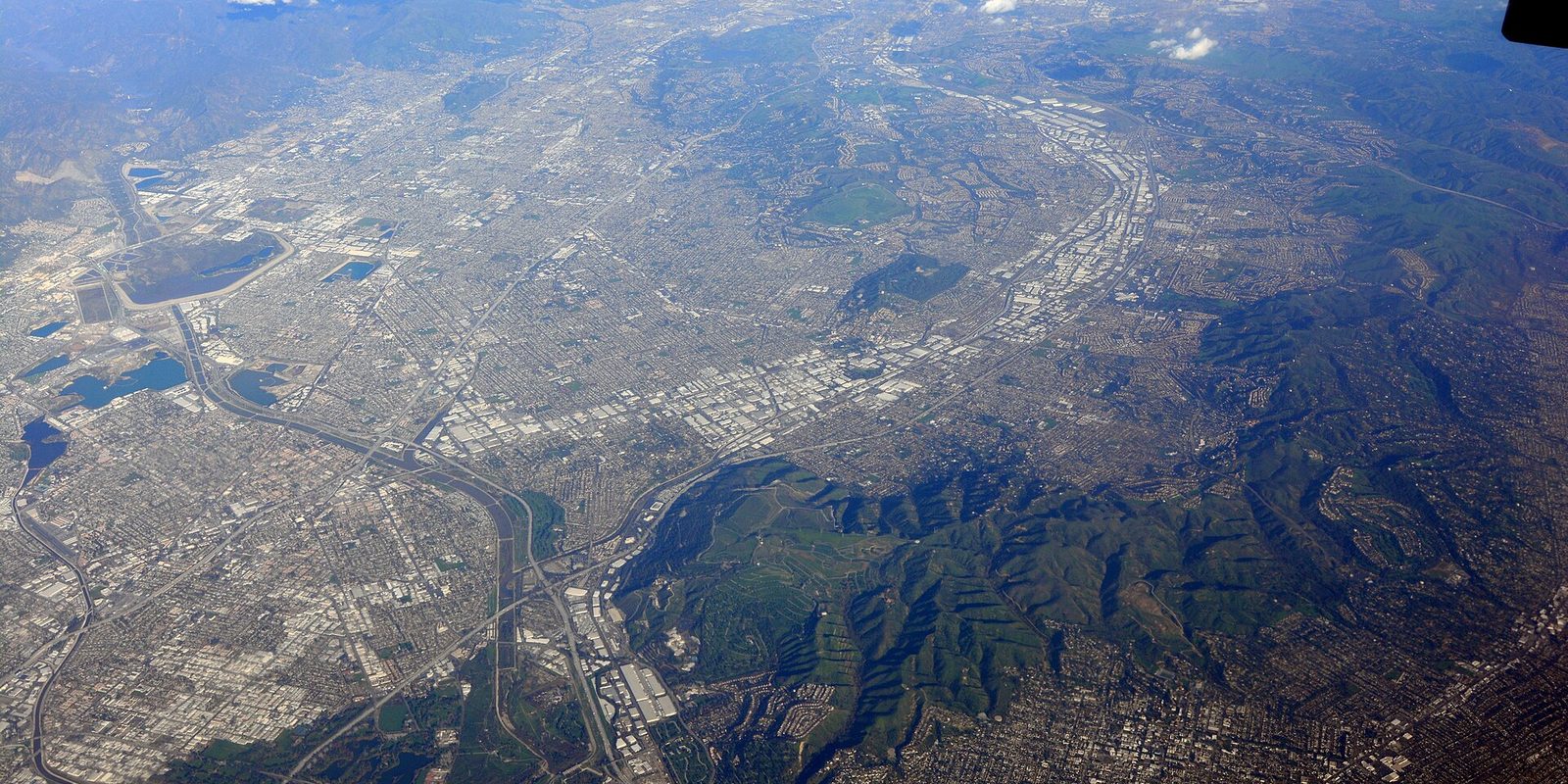 San Jose from high above, the valley's street grid and low industrial blocks running from bay salt ponds to green hills