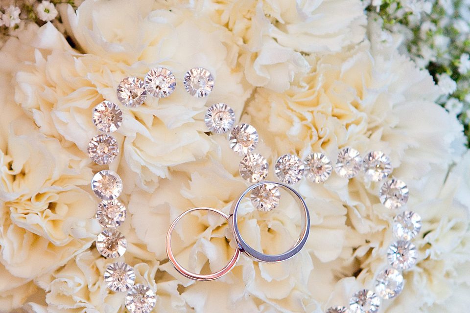 Two wedding bands and a curve of small diamonds resting on cream coloured roses