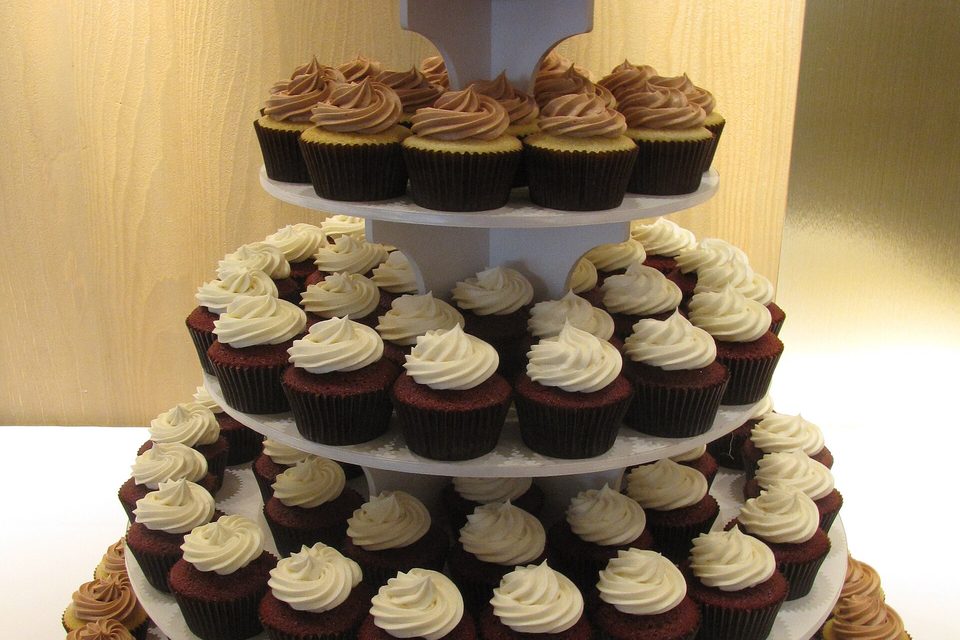 A three tier stand holding dozens of cupcakes with swirled white and chocolate frosting