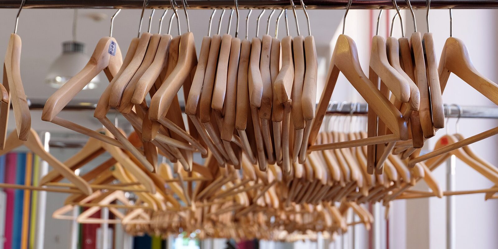 Rows of empty wooden hangers packed tightly on a rail in a bright shop