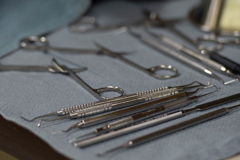 Stainless steel dental instruments laid out in rows on a blue cloth tray
