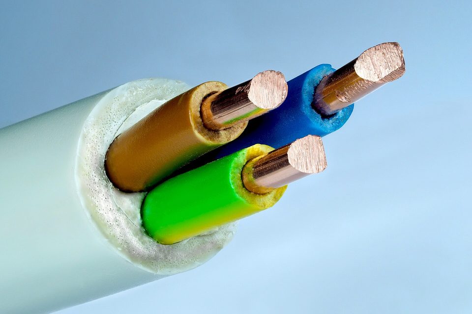 Cut end of a three-core electrical cable showing bare copper conductors in brown, blue and green-yellow sleeving