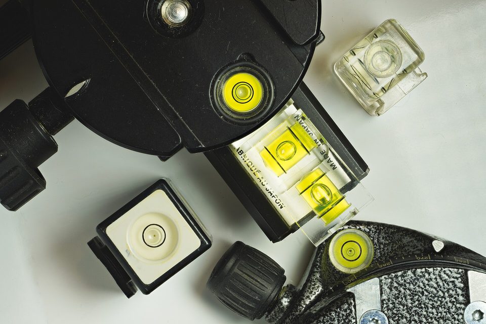 Close-up of several spirit levels and bubble vials with bright yellow fluid on a white surface