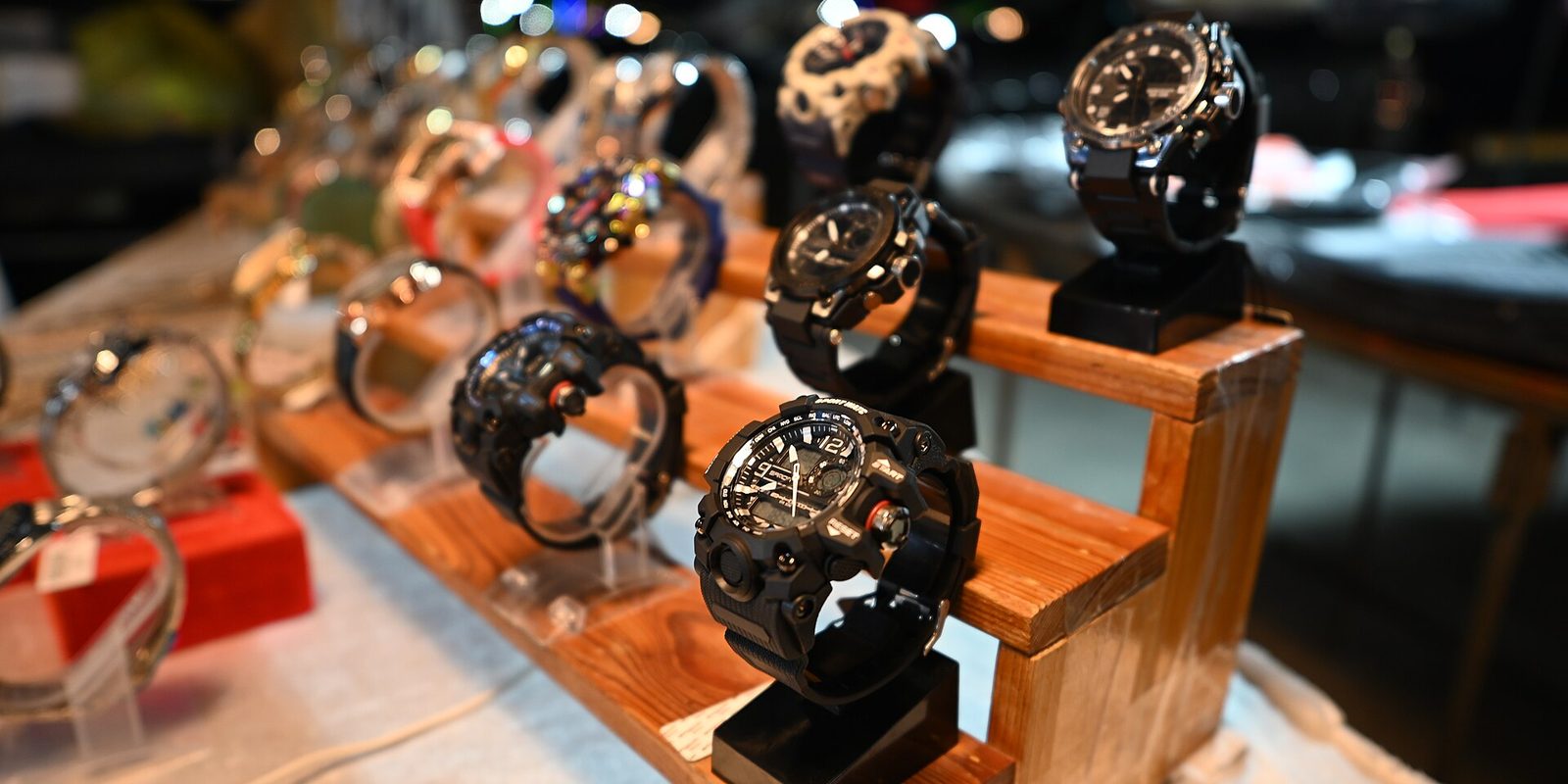 A row of chunky black sport wristwatches on wooden display stands at a retail counter